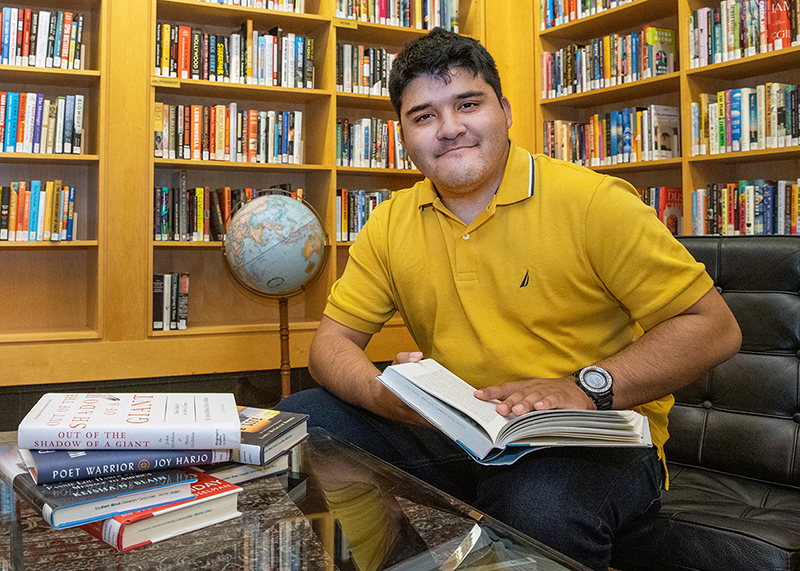 SIU history student Carlos Gomez sits at a desk surrounded by history books
