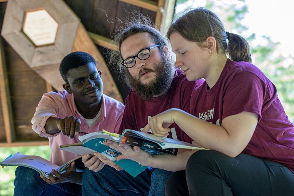 Three SIU students study a book in the Faner Hall breezeway